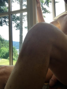 nude man relaxing near a window