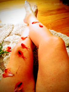 woman's bare legs, crossed, decorated with flower petals