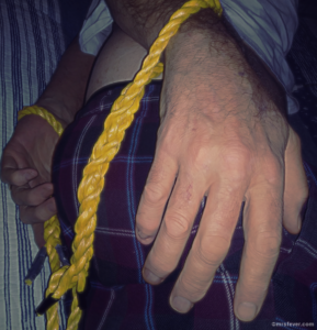 man's hands cuffed with nautical eye-splice ropes