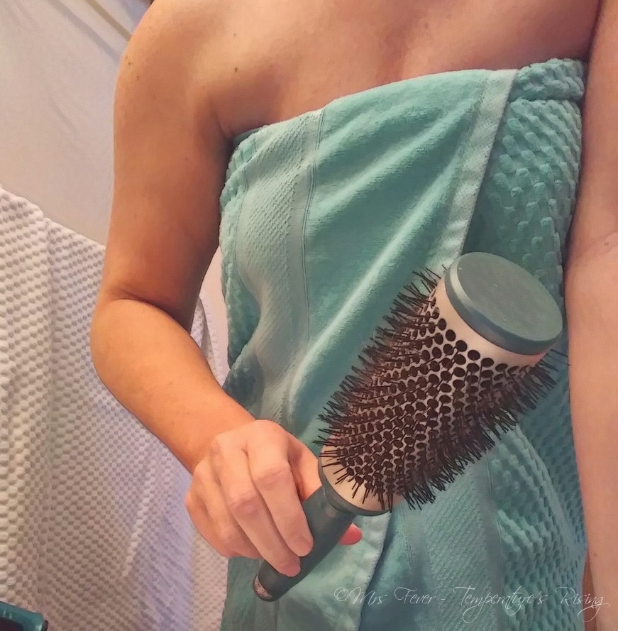 woman wrapped in towel holding roundbrush
