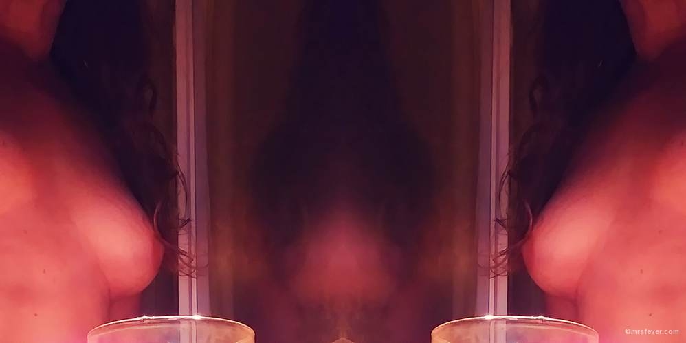 mirrored image of bare-breasted woman holding a candle, creating a ghost-like effect
