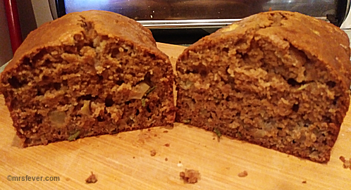 open-faced half-sliced loaf of rosemary apple bread on cutting board