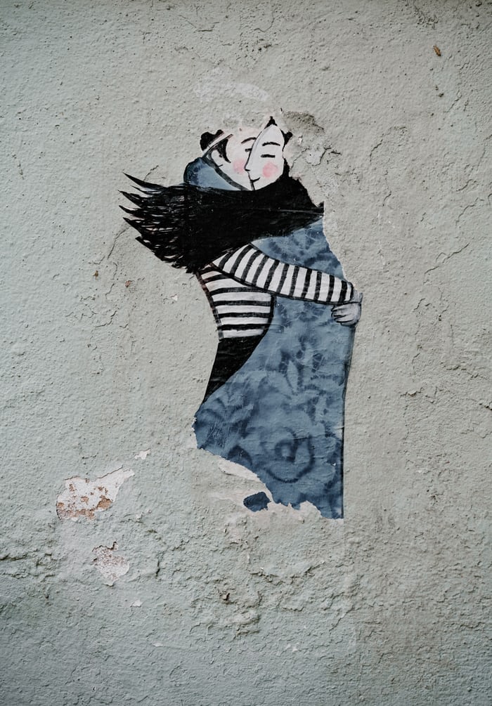mixed media on concrete of man and woman hugging, from Unsplash