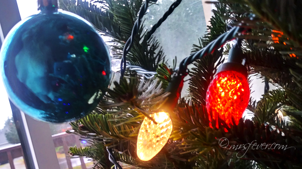 landscape photo of blue bauble on Christmas tree containing the reflection of nude woman