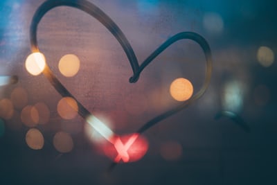 heart drawn on fogged window with blurred lights reflected, image from Unsplash