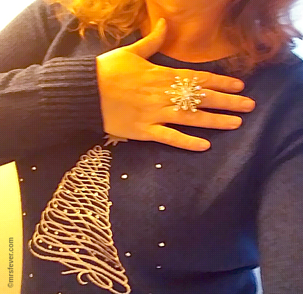 woman wearing blue Christmas sweater featuring an embroidered Christmas tree, and a shiny crystal snowflake ring