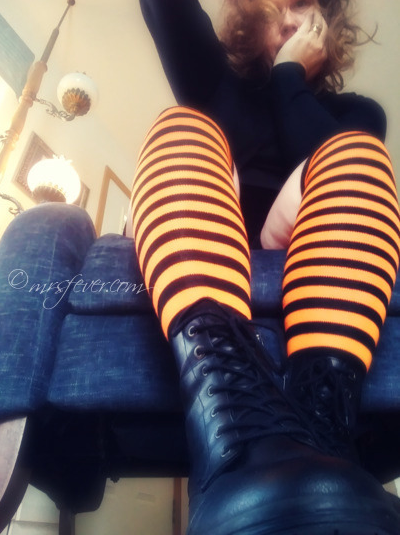 up-from-below shot of woman wearing orange and black striped over-the-knee socks, seated in blue chair