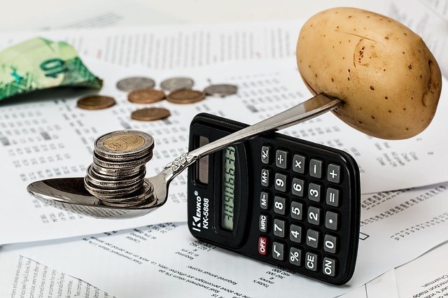 potato and coins balanced on a spoon over top of a calculator -- money management image from Pixabay