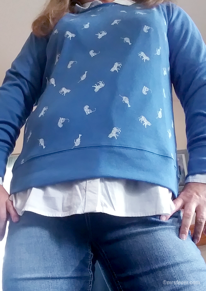 woman standing with hands on hips wearing blue sweatshirt with small white tigers on it