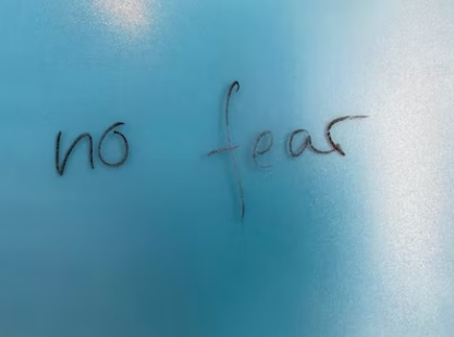 No Fear in black handwriting on blue background, via Unsplash