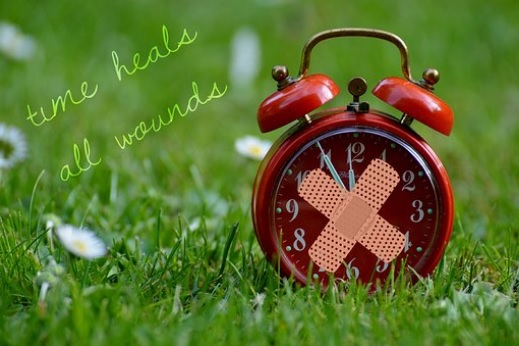 alarm clock with band-aid over the glass, labeled Time Heals All Wounds, via Pixabay